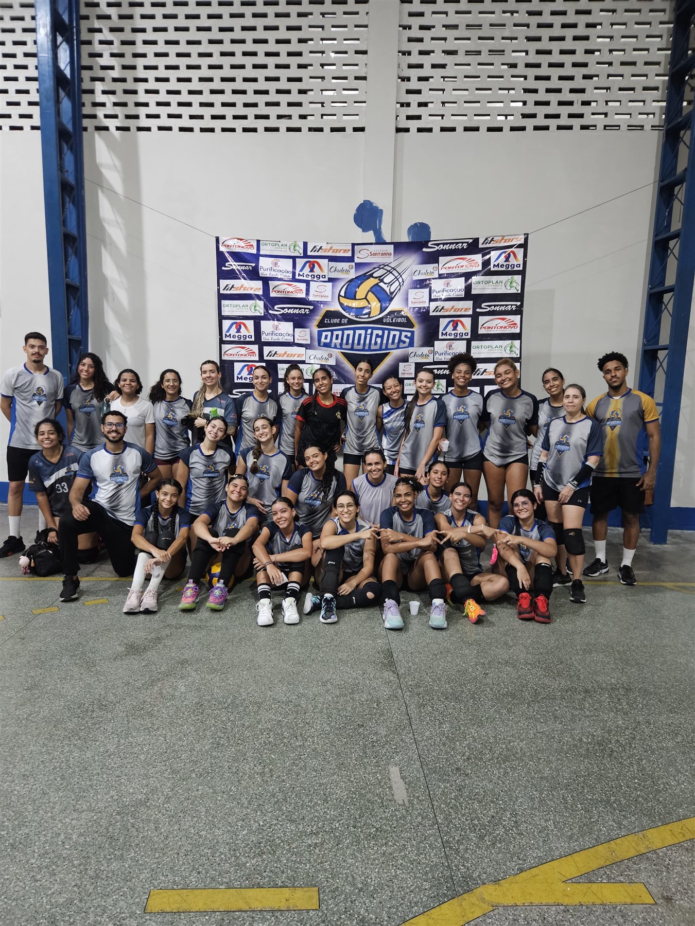 Grupo grande de atletas do Prodígios reunido em frente ao mural do clube