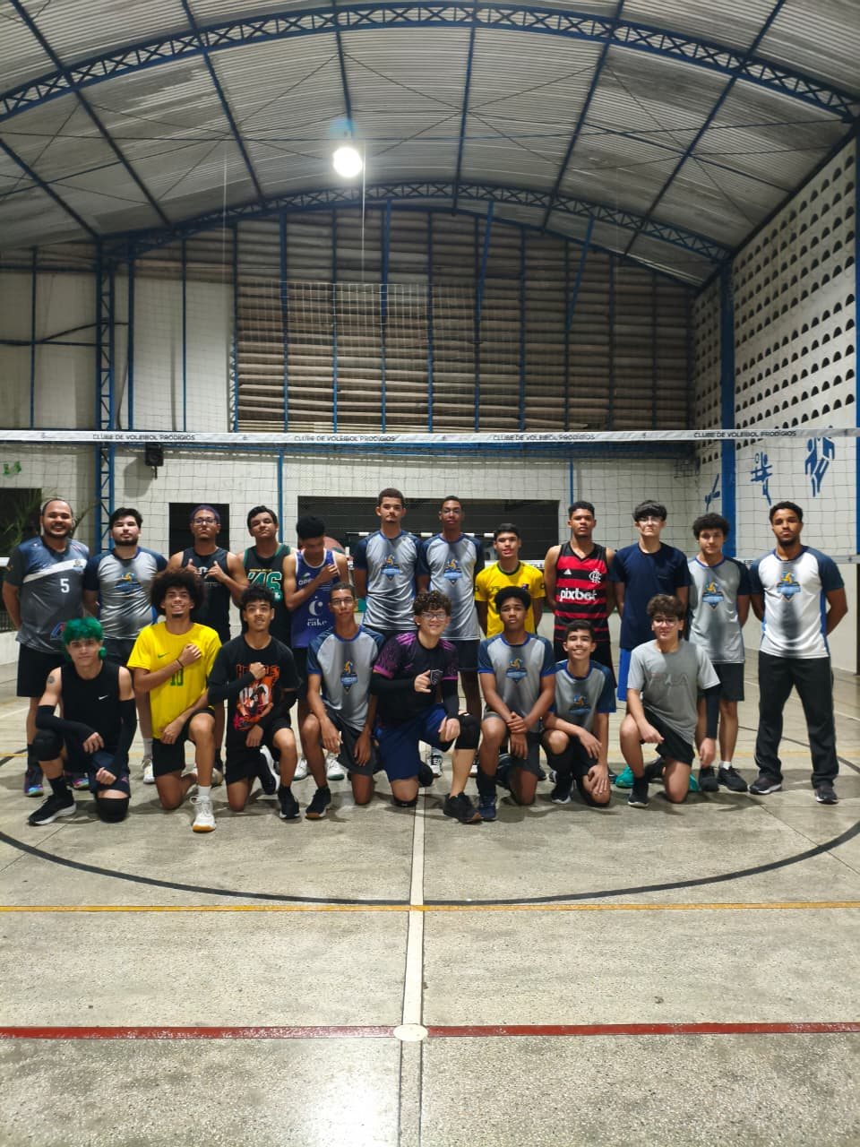 Grupo de atletas jovens do Prodígios reunido em frente ao mural do clube