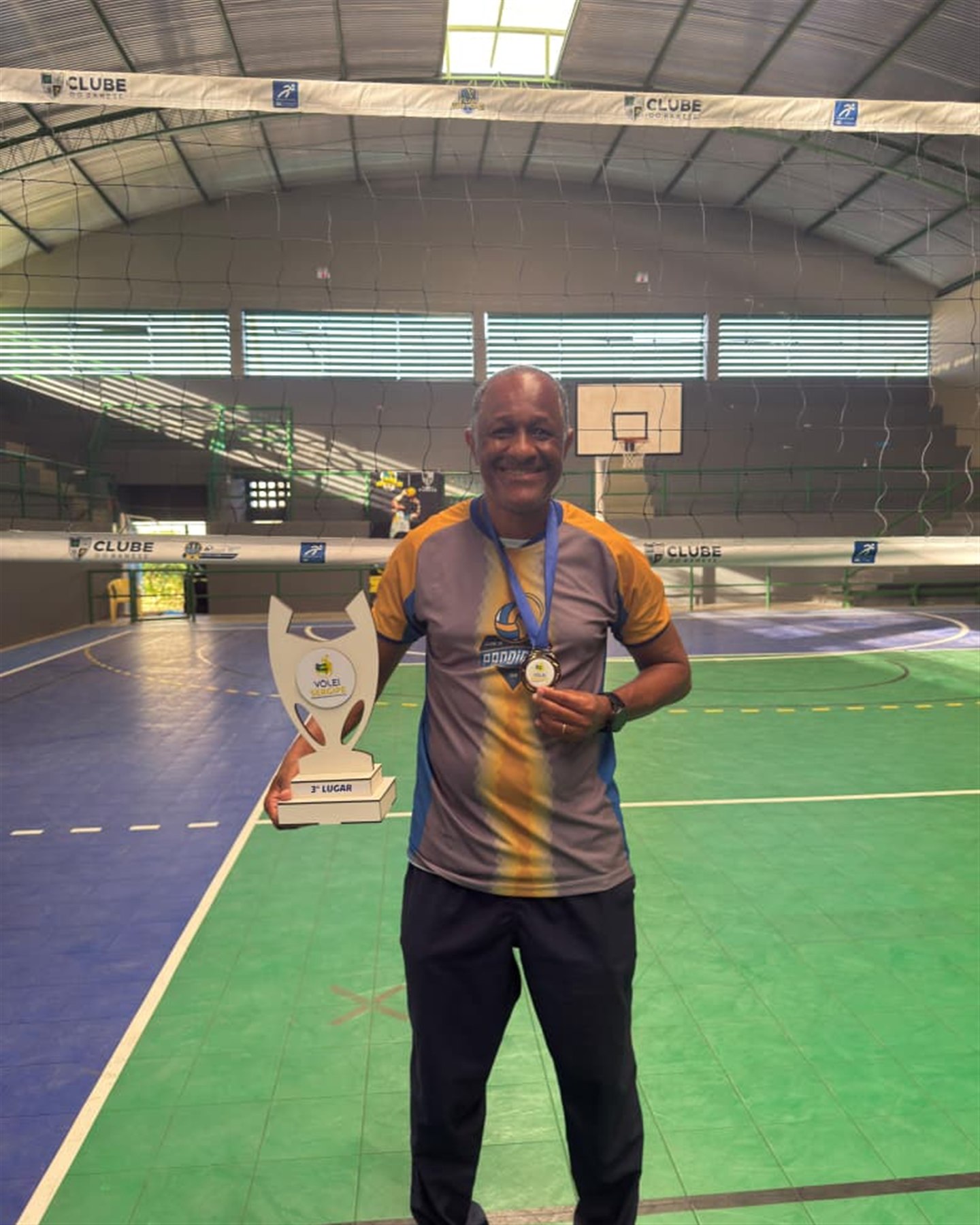 Membro da comissão técnica do Prodígios com o troféu de 3º lugar e a medalha do Vôlei Sergipe